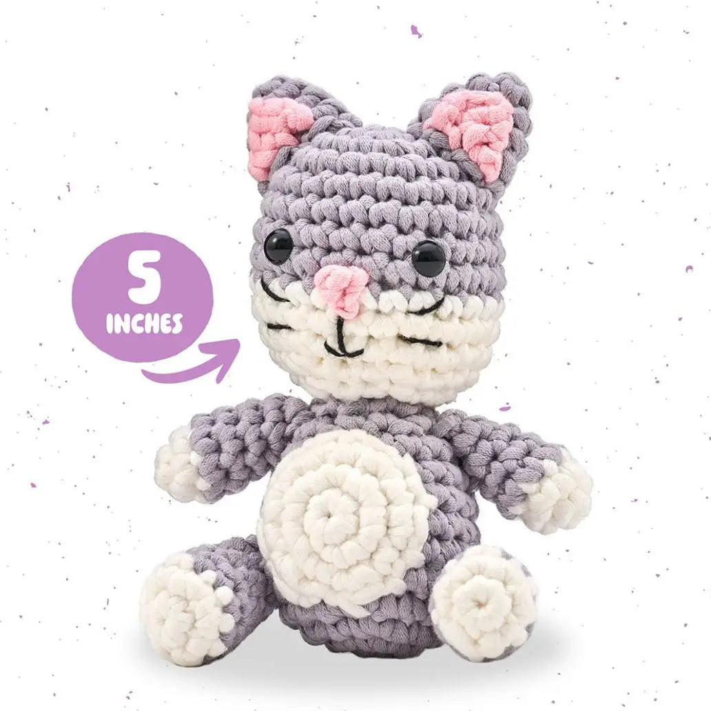 Crocheted cat toy with gray and white colors on a light speckled background