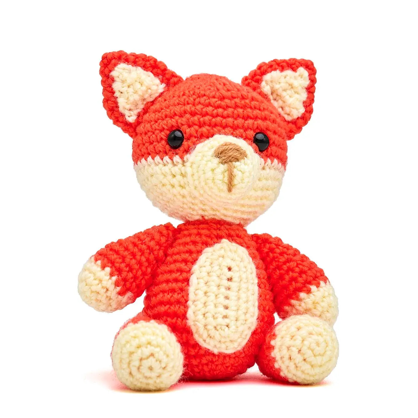 Crocheted fox toy with red body and cream-colored face and paws on a white background